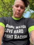 Selfie of Amy and her shirt which reads "Drink water, love hard, fight racism"
