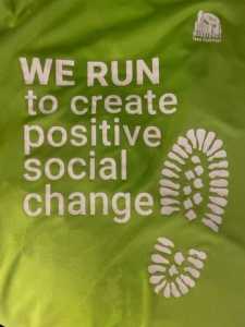 Green t-shirt which reads "We run to create positive social change"